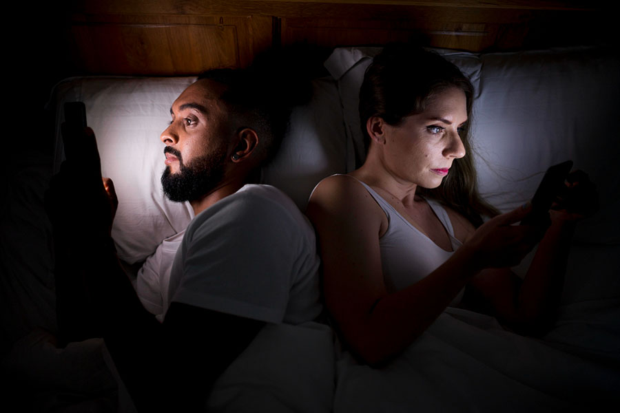Homme et femme dans un lit sur leur téléphone portable qui ne se parle pas. Perte de libido.