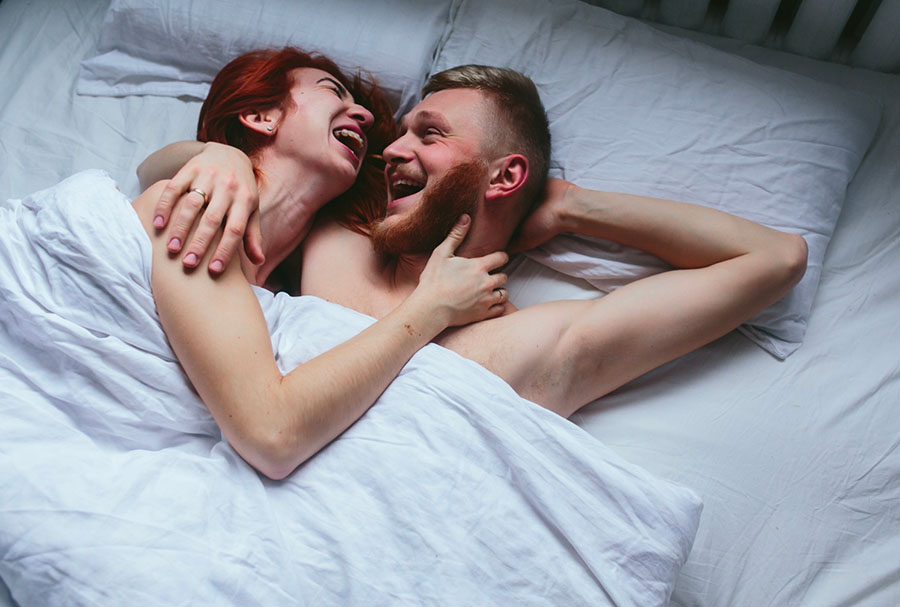 Couple dans un lit complice en train de rigoler