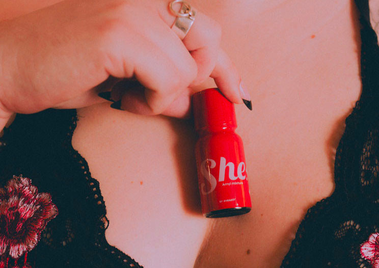 femme qui tient un poppers rouge "She"